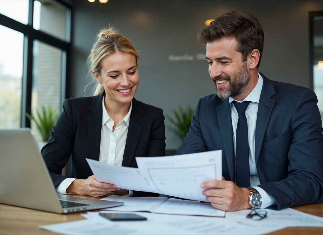 Insurance Solutions - Two Professionals Looking Over Some Documents in a Conference Room